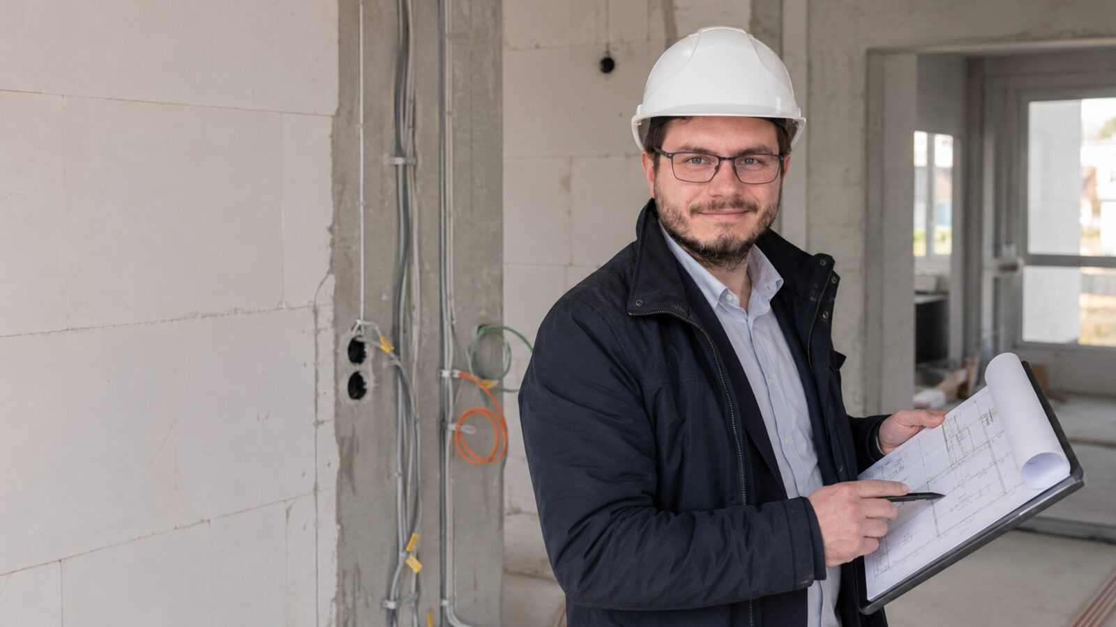 Sachverständiger prüft Elektroinstallation im Neubau mit Planunterlagen